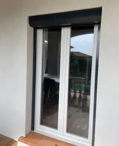 Fenêtre double avec menuiserie blanche équipée d’un volet roulant aluminium gris anthracite avec coffre extérieur, installé pour amélior